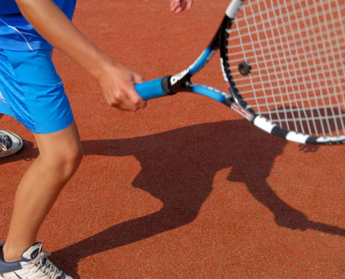 A Person Holding a Tennis Racket on the Red Ground